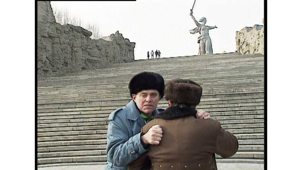 A frame from Trauma Zone showing two men on a staircase below a famous Soviet statue.