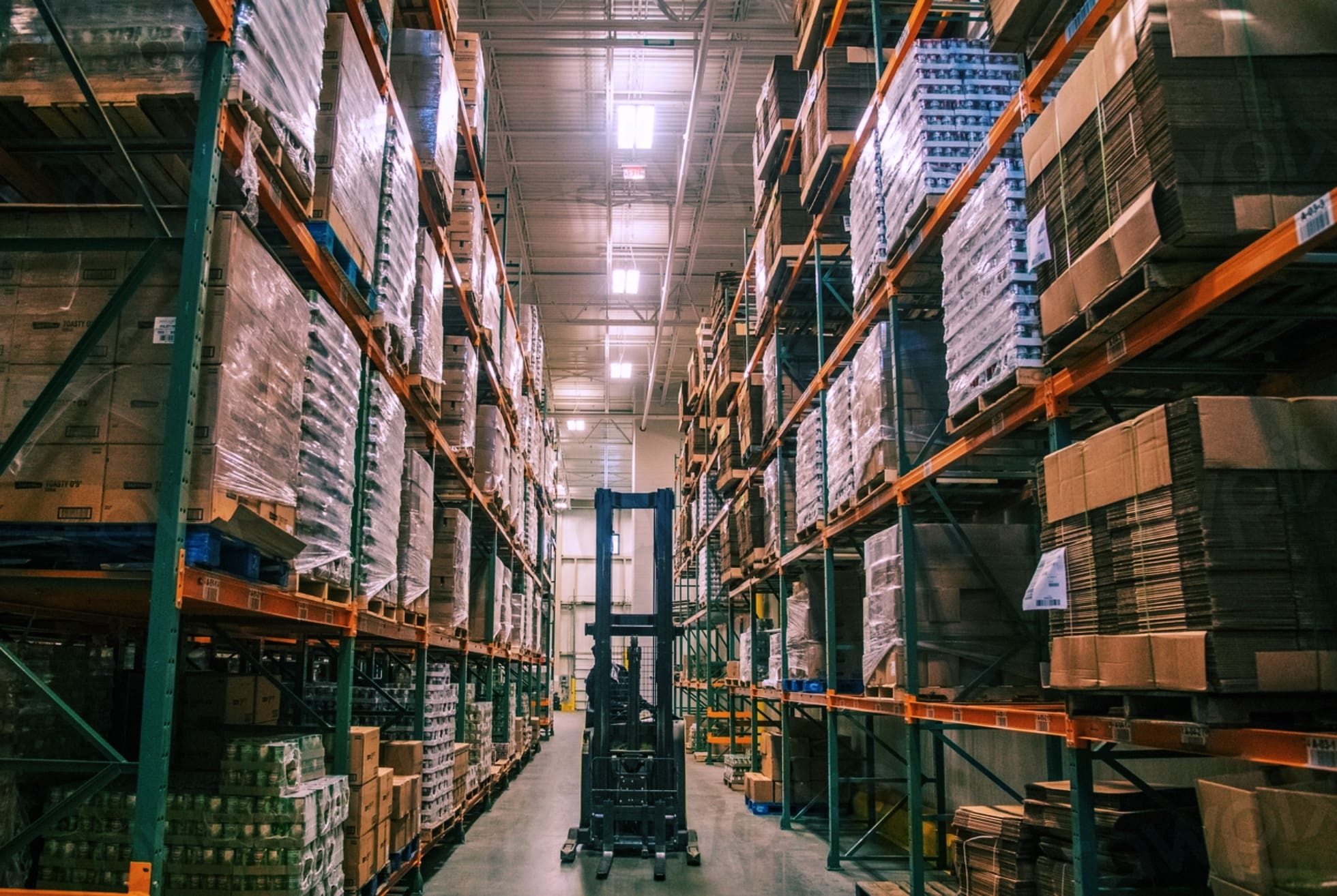 A large warehouse with a forklift between shelves.