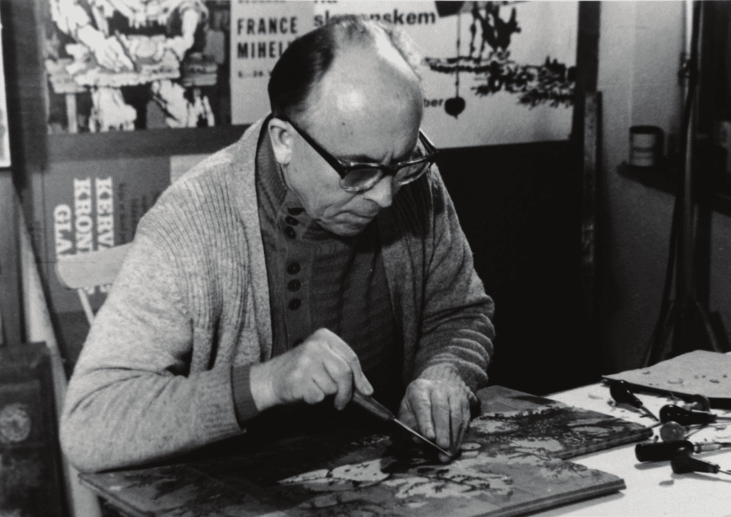 A black and white photo of France Michelic, painting at a table.